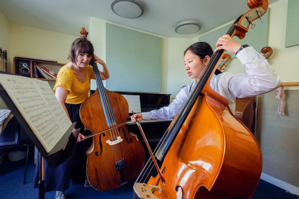 Two people, a student and a teacher, playing the cello at The King's Summer School's Music and Performance Academy.