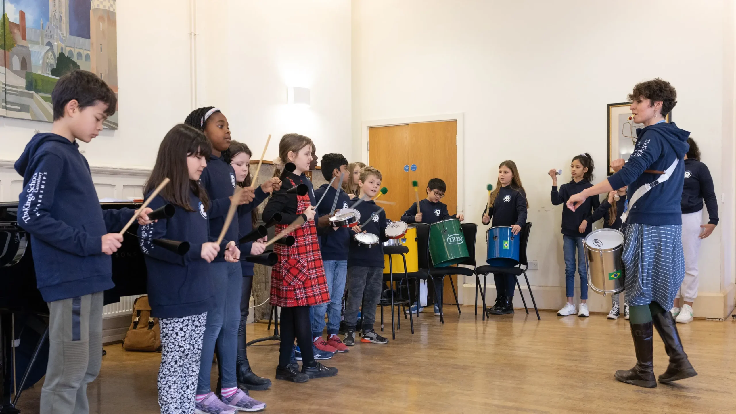 A group of young music students being led by their teacher in a drumming lesson at Music and performance academy